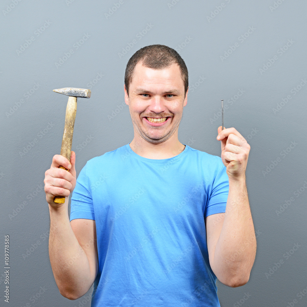 Portrait of funny man holding hammer and nail Portrait of funny man holding hammer and nail