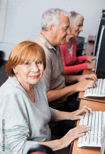 Happy Senior Woman Using Computer In Classroom