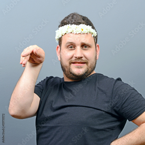 Portrait of funny chubby man wearing flower wreath on head and b photo