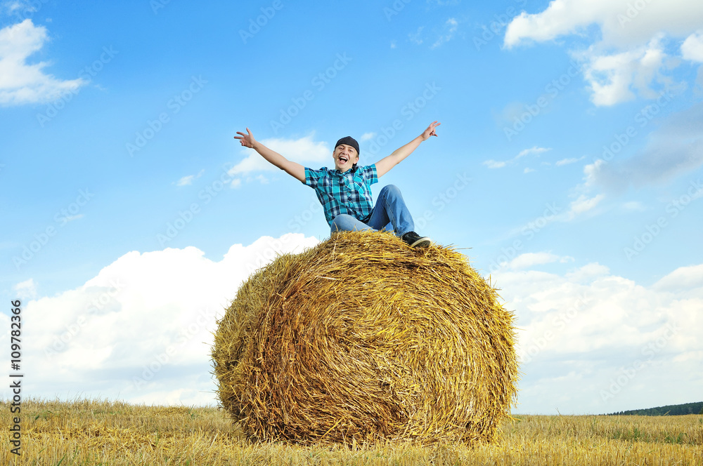 man on a stack of straw against a field man on a stack of straw against a field
