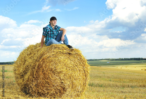 man on a stack of straw against a field