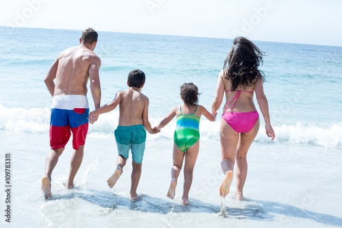 Rear view of family running towards sea 