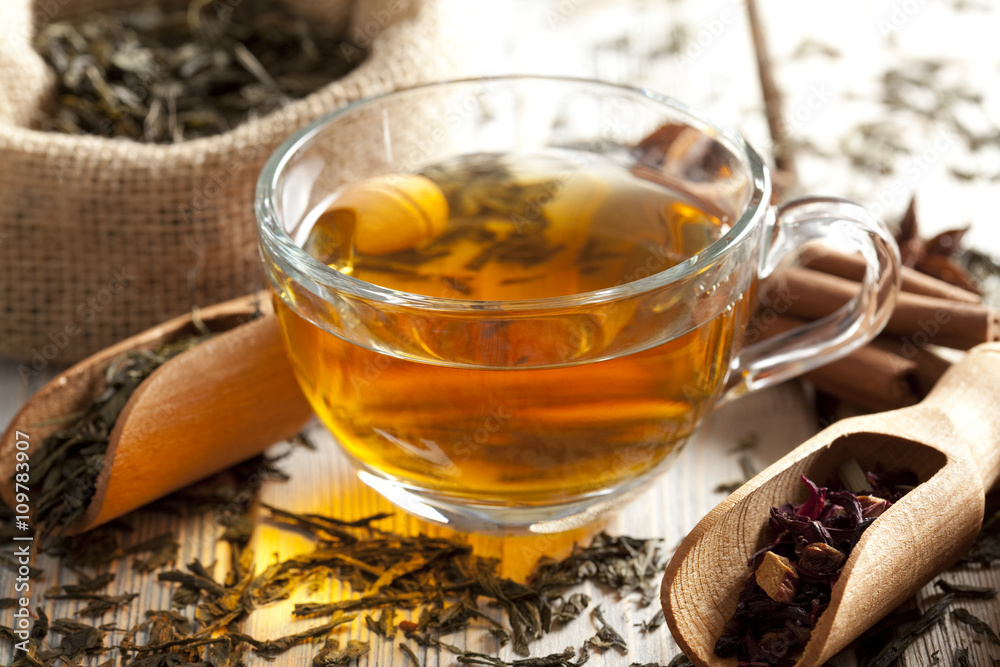Cup of tea and mix of assorted tea leaves on wooden table Cup of tea and mix of assorted tea leaves on wooden table