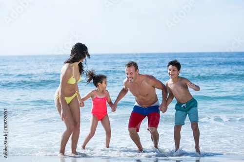 Family in swimwear holding hands while enjoying