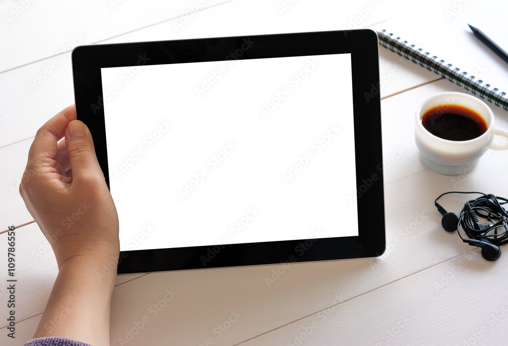 Hand holding tablet with isolated screen on wooden desk Hand holding tablet with isolated screen on wooden desk