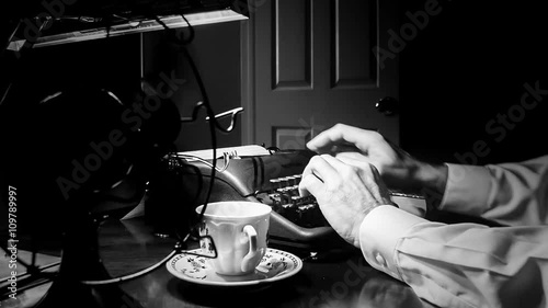 Dimly lit Film Noir setting of a man typing on a 1940 manual typewriter with an old electric fan and classic teacup and saucer close by.