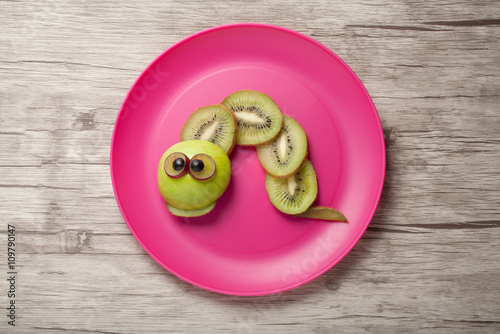 Caterpillar made of kiwi, apple and grape on plate