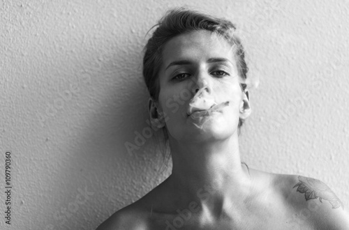 Black and white portrait of pensive young woman smoking