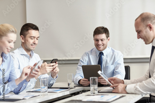 smiling business people with gadgets in office