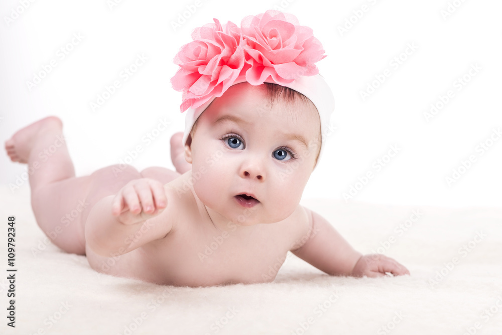 cute little baby girl with pink bow flower on her head. kid looks into the camera with admiration. child girl with big blue eyes. happy family concept cute little baby girl with pink bow flower on her head. kid looks into the camera with admiration. child girl with big blue eyes. happy family concept