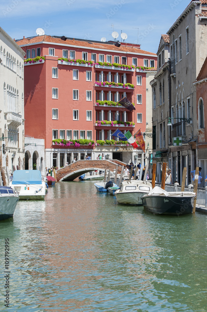 View of the streets of Venice, parked boats and leisure travelers. Vertical frame.