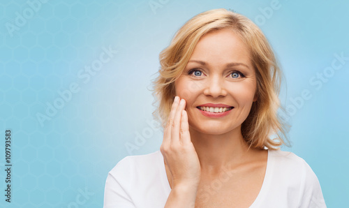 smiling woman in white t-shirt touching her face