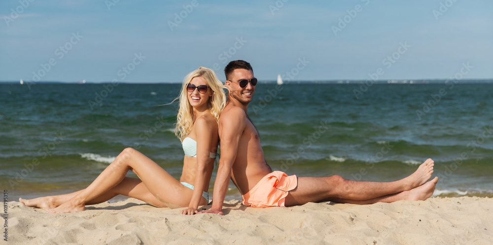 happy couple in swimwear sitting on summer beach happy couple in swimwear sitting on summer beach