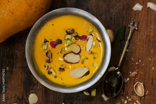 Mango pudding with nuts and cream served in a metal serving dish photo