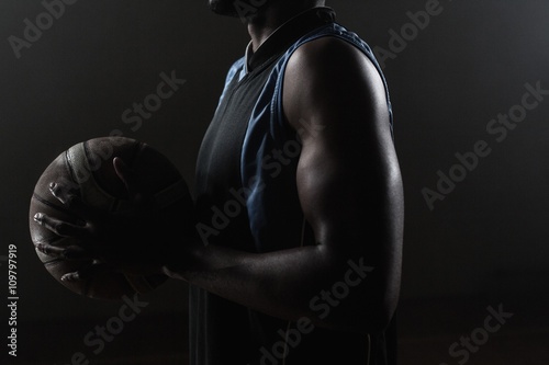 Zoom on a side of  a basketball player holding a basketball © WavebreakMediaMicro