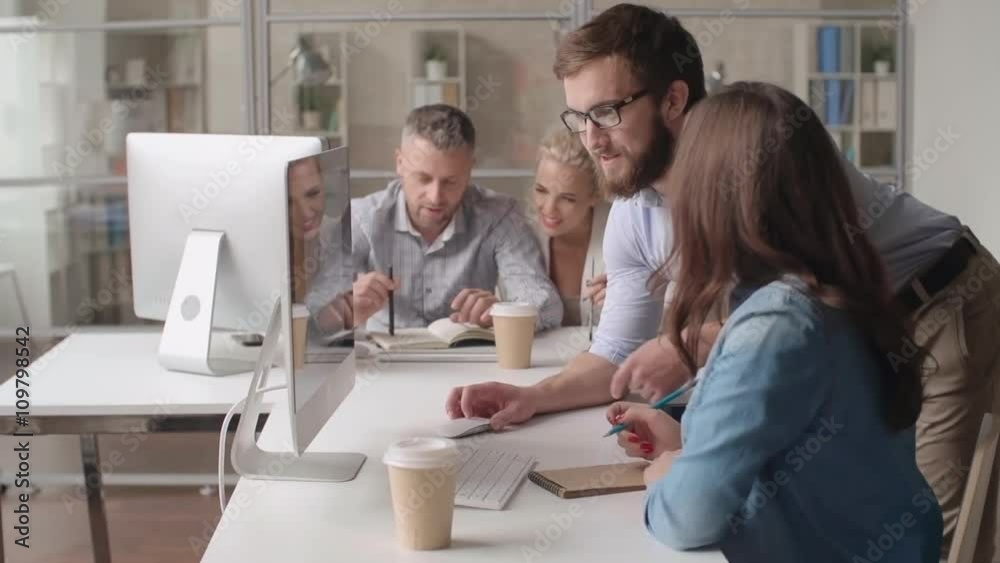 Businessman explaining something on a computer screen to his female colleague Businessman explaining something on a computer screen to his female colleague