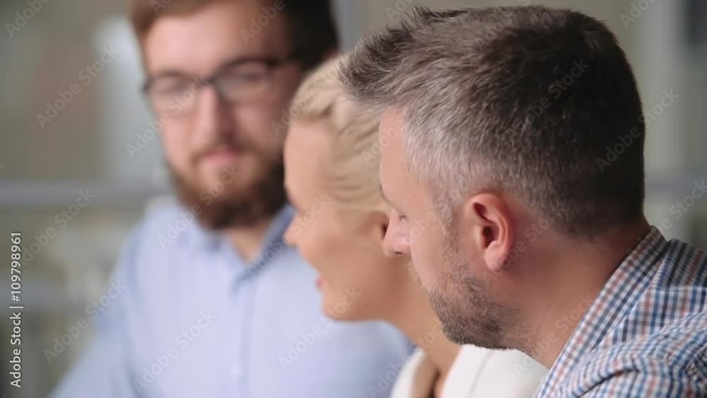 Bored businessman looking away and thinking about something; his defocused colleagues having a discussion in the background Bored businessman looking away and thinking about something; his defocused colleagues having a discussion in the background