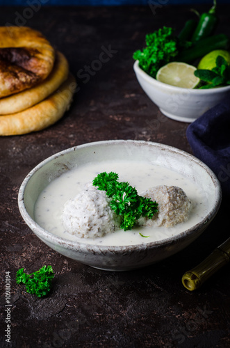 Kibbeh bil laban - arabian yogurt soup with stuffed bulgur cutletson dark background. Selective focus photo