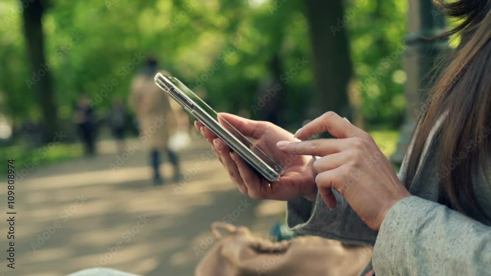 Woman hands using smartphone in city park
