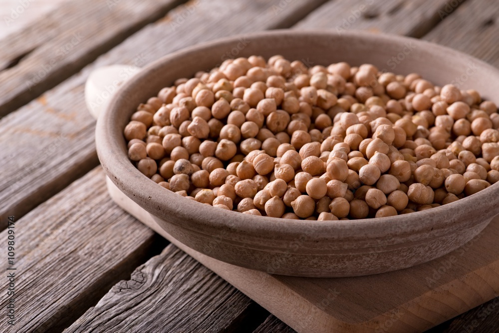 Earthen bowl with chickpeas on chopping board