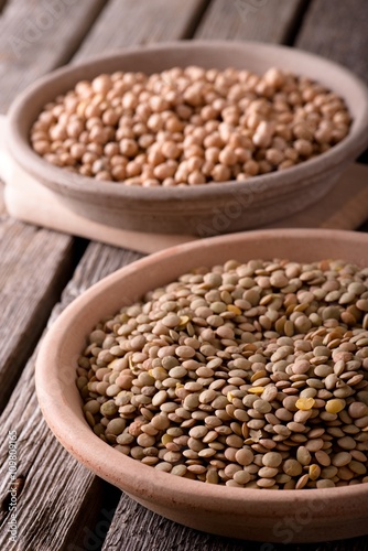 Clay bowls with lentils and chickpeas on wooden board