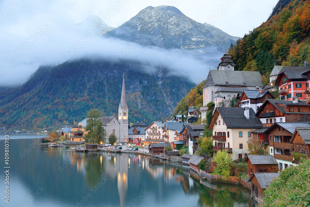 Early morning view of Hallstatt, a charming lakeside village in Salzkammergut region of Austria, with reflections on smooth lake water in colorful autumn season ~ A beautiful UNESCO heritage site