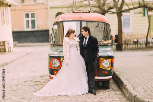 Happy married couple empracing near colorful retro car photo