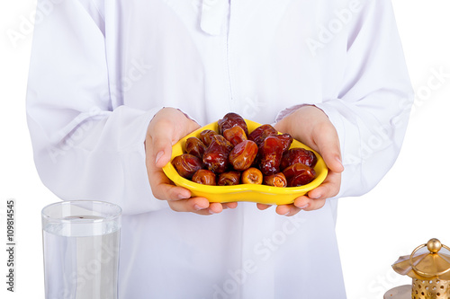 Little Muslim kid presenting a dish of dates in Ramadan photo