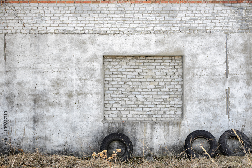Fototapeta premium White brick and concrete wall exterior texture outside with tires next to it.
