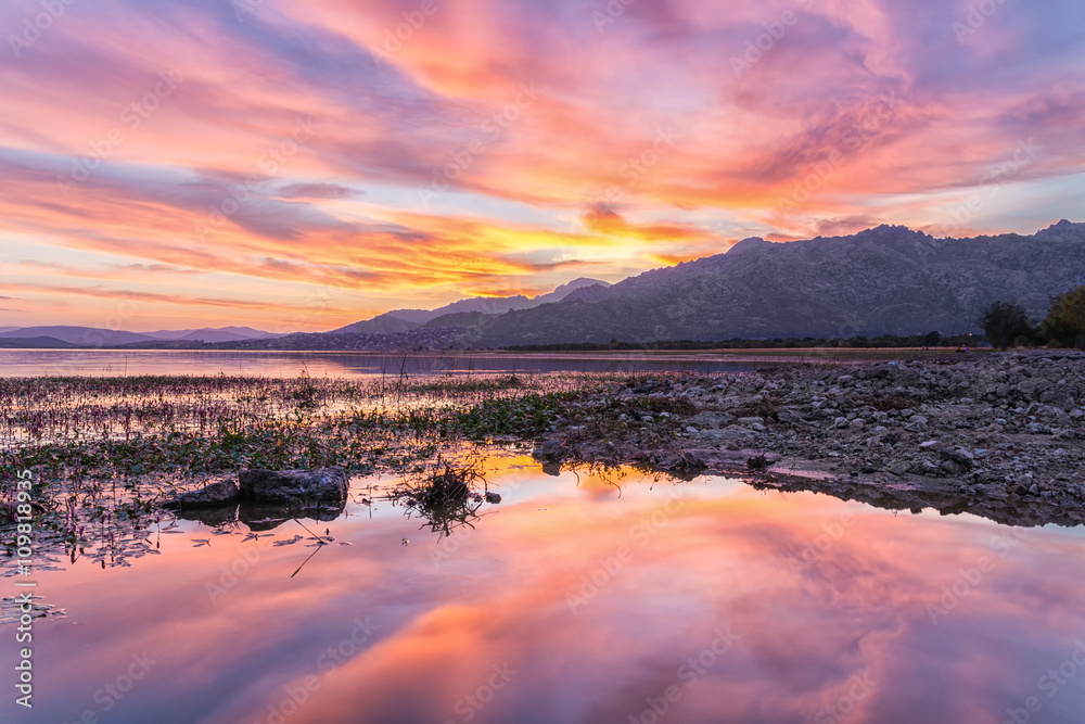 Colorful sunset reflected in the lake with the mountains at the background