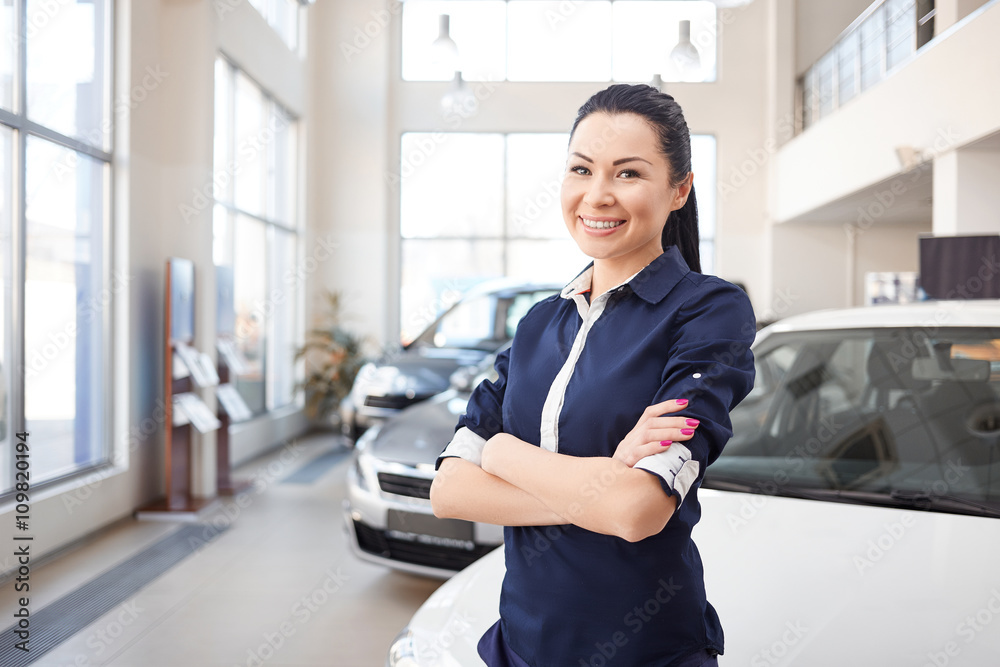 Φωτογραφία happy smiling saleswoman standing in the new car showroom