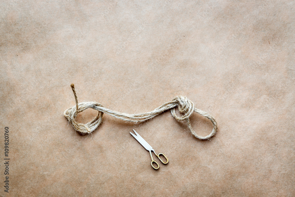 concept scissors cut knot on rope at background kraft paper concept scissors cut knot on rope at background kraft paper