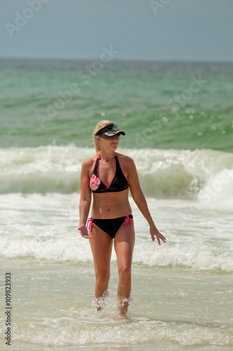 Mom in bikini swimsuit walking in ocean at the beach.
