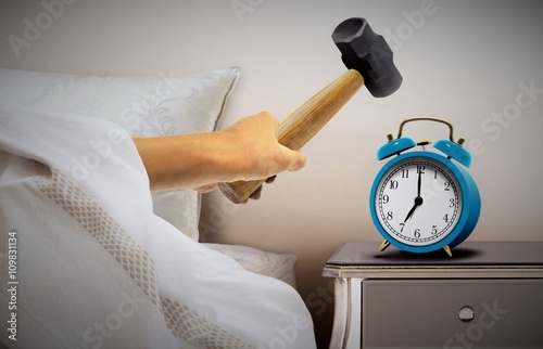Man smashing alarm clock with sledge hammer