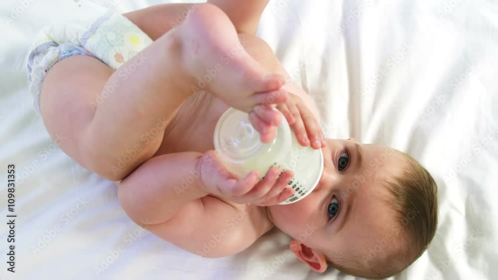 A baby is drinking his feeding bottle