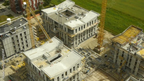 Passing, camera fix, rear view above crane and construction site.
