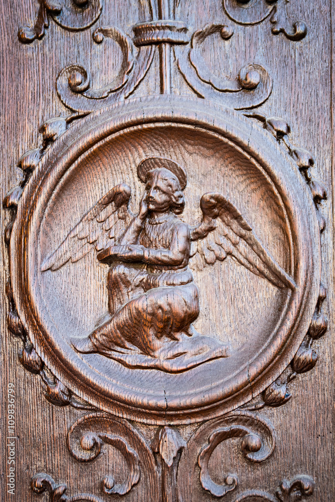 Angel engraved on the wooden portal of an ancient church.