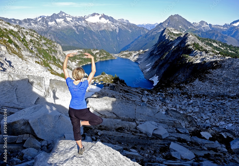 Naklejka premium Fit Blond Woman in Yoga pose Meditating by Alpine Lake. Hidden Lake, North Cascades National Park, Washington State, USA. 