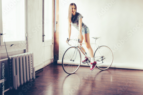 Young woman on white retro bicycle in studio