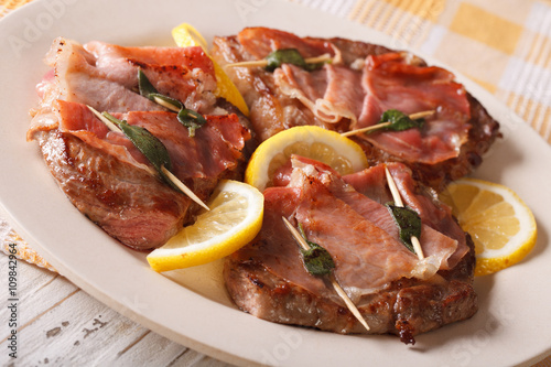 Italian cuisine: beef saltimbocca with lemon close up. horizontal
