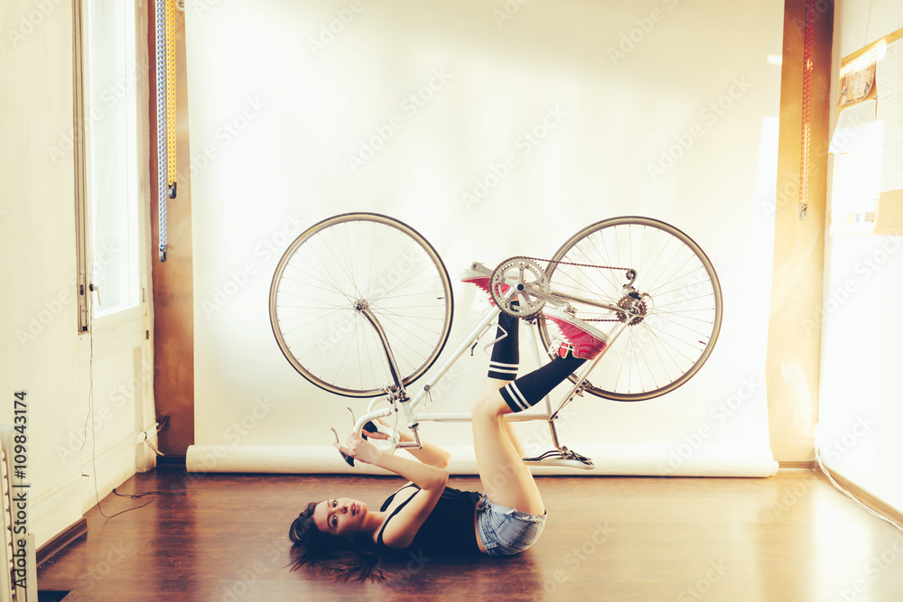 Young woman on white retro bicycle in studio