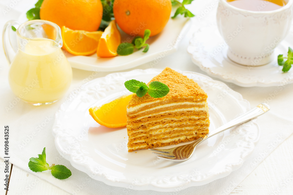 Homemade honey cake with orange cream on a white plate. Homemade honey cake with orange cream on a white plate.