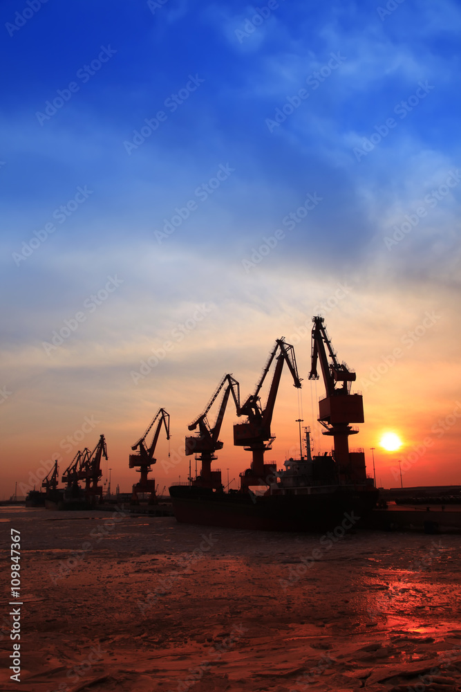 In the evening, the silhouette of port cranes In the evening, the silhouette of port cranes