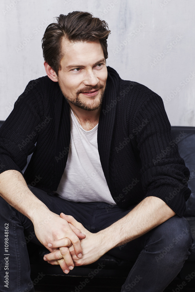 Good looking guy sitting on sofa, looking away Good looking guy sitting on sofa, looking away