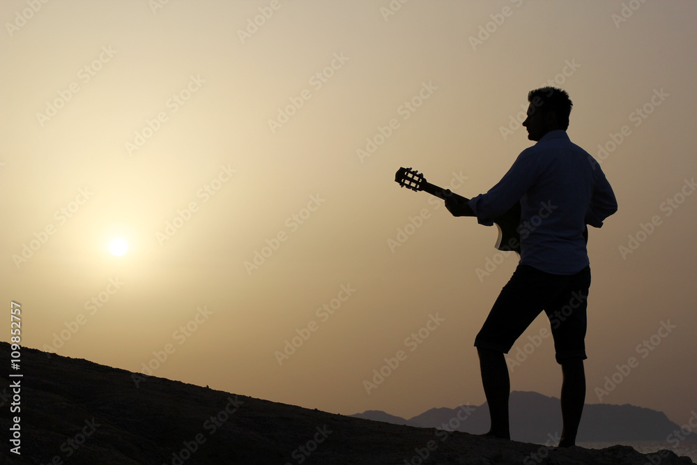 dark silhouette of a man musician playing guitar