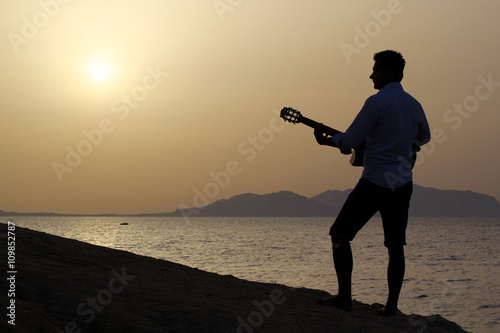 dark silhouette of a man musician playing guitar