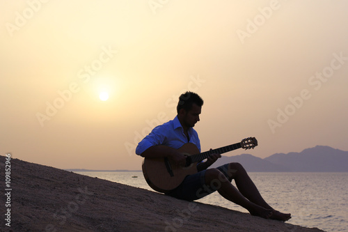 Fototapeta Naklejka Na Ścianę i Meble -  musician on the beach playing guitar