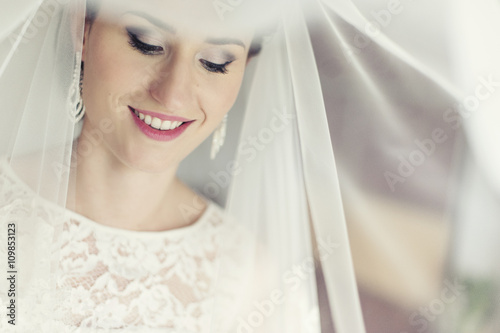 Uśmiechnięta panna młoda na tle swojego welonu w dniu ślubu - przygotowania