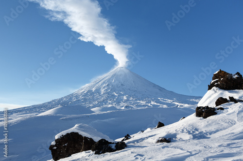 Beautiful winter volcanic landscape: view of eruption active Klyuchevskoy Volcano (Klyuchevskaya Sopka) in clear weather, sunny day. Russian Far East, Kamchatka, Klyuchevskaya Group of Volcanoes.