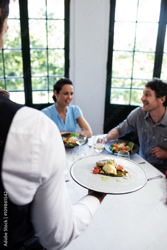 Waiter serving meal to customers Waiter serving meal to customers